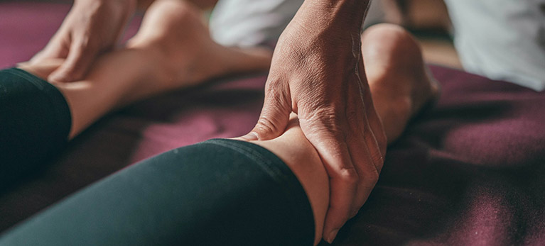 Image of a Kinesiologist massaging a clients’ achilles tendons